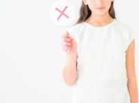 若い女性が✕の表示を持っている